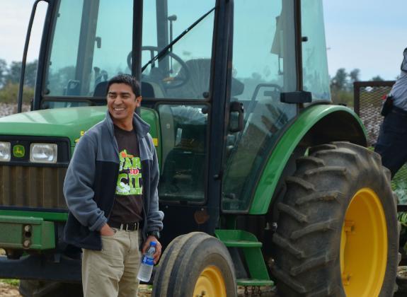A photo of Dr. Pratap Devkota by a tractor